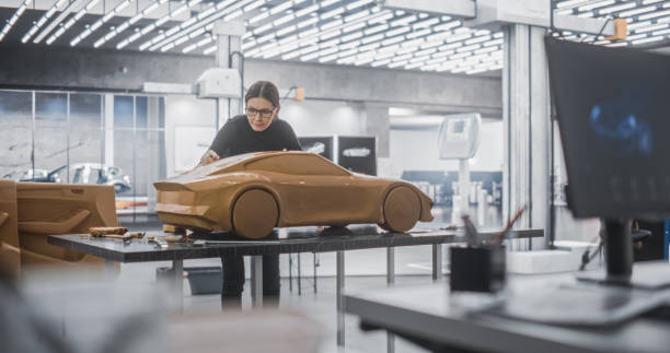 istock Car Modeler Enjoying Creative Work Process on a Concept Car Made Out of Plasticine Modeling Clay. Handsome Designer Using Spatula to Smooth the Prototype Model of an Electric Vehicle 1516871374