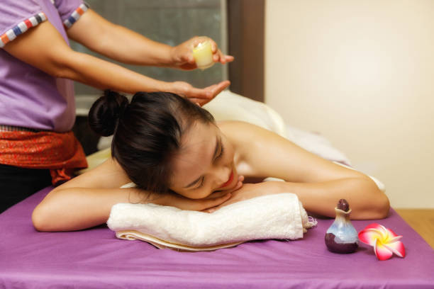 femme asiatique profitant d’un massage du dos avec de l’huile de massage chaude provenant d’une bougie dans un salon de massage. concept de soins de beauté. - ayurveda massaging aromatherapy chakra photos et images de collection