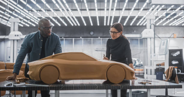 istock Enthusiastic Teamwork of Two Diverse Creative Colleagues Working in Automotive Development Design Agency. Professional Sculptor Working Together with an Engineer, Discussing Prototype Vehicle 1516871396