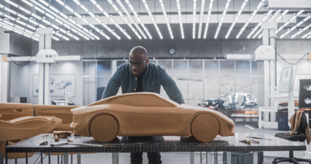 istock Black Creative Automotive Designer Working on a Prototype Car Out of Polymer Modeling Clay. Focused Professional African Modeler Contemplating the 3D Sculpture, Looking Thoughtfully at the Model 1516872067
