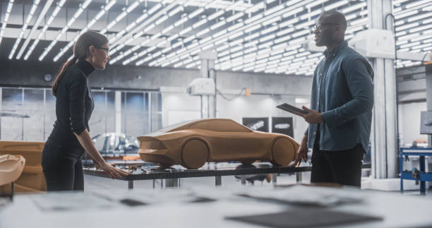 istock Enthusiastic Teamwork of Two Diverse Creative Colleagues Working in Automotive Development Design Agency. Professional Sculptor Working Together with an Engineer, Discussing the Prototype Vehicle 1516873881