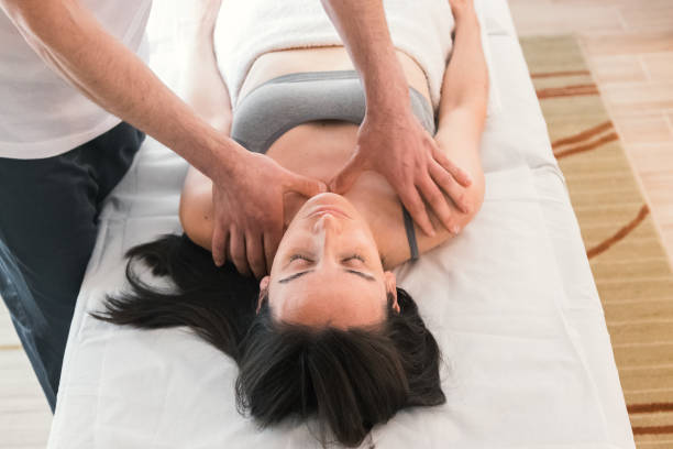 젊은 백인 여성은 통증을 완화하거나 신체 상태를 개선하기 위해 치료사의 치료를 받고 있습니다. 이완 및 호흡 운동. - torso physical therapy patient relaxation exercise 뉴스 사진 이미지