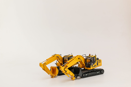 Two yellow excavator   model   on  a white background,with copy space