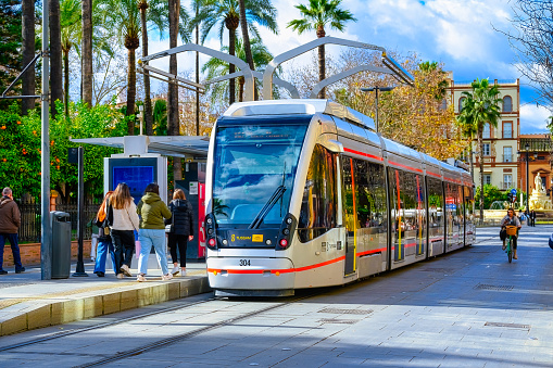 Seville, Spain - January 20, 2023: City tram bus on a street. The public transportation vehicle is painted silver grey.