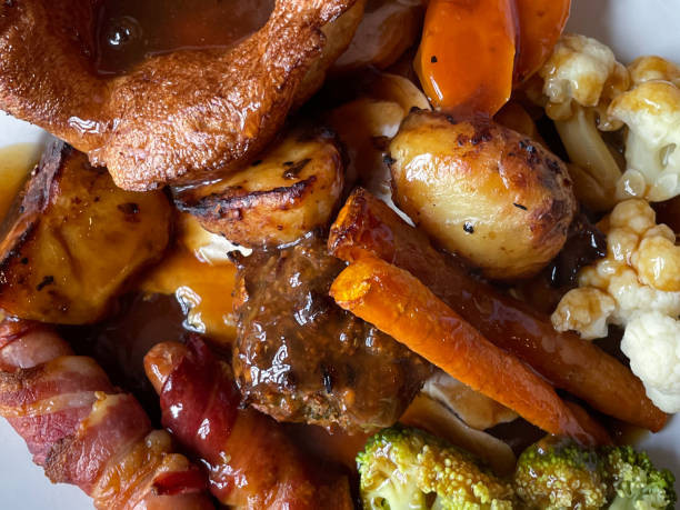 istock Full frame image of white plate containing Sunday roast dinner meal, Yorkshire pudding, carrots, roasted potatoes, cabbage, broccoli, pigs in blankets, chicken breast and sage and onion bread stuffing, gravy, elevated view 1516911290