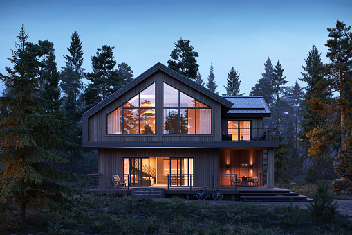 3d render of forest house with large windows and surrounded by trees during night. Digitally generated image of a luxurious style forest bungalow during evening.