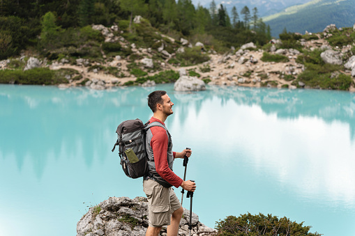Caucasian man admiring the beauty of the turquoise-colored Sorapis Lake, during hike
