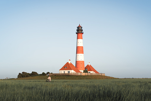 girl with a bicycle on the background of Westerheversand Lighthouse in Germany