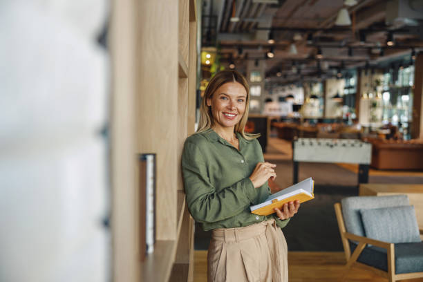 istock Pretty woman entrepreneur making notes in note pad while standing on cozy coworking background 1517018680