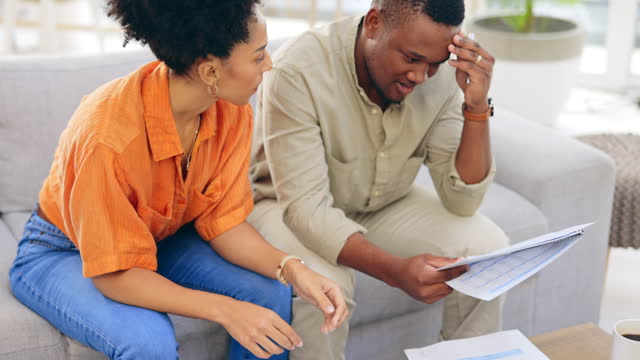 Black couple, documents and financial crisis on living room sofa discussing mortgage payment or loan at home. Frustrated African man and woman with paperwork in debt, finance issue or money problems