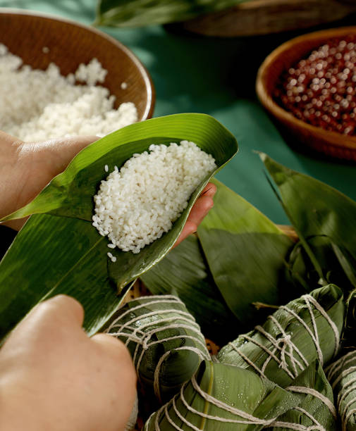 zongzi, boulettes de riz, fait avec du riz gluant et de la viande ou du jaune d’œuf (dattes et haricots rouges), enveloppé dans des feuilles de zong, un aliment commun pour le festival des bateaux-dragons dans les pays asiatiques. - hokkien photos et images de collection