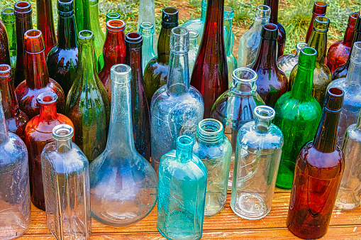 A collection of antique bottles of various sizes, shapes and colors displayed at a Cape Cod flea market.