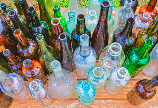 A collection of antique bottles of various sizes, shapes and colors displayed at a Cape Cod flea market.