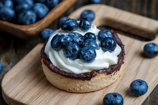 Tartlet with cream and blueberry flavor, sweet dessert with cream and ripe blueberries