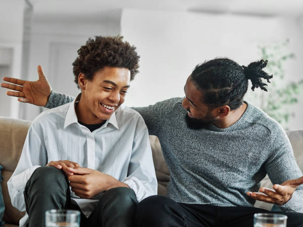 father son family man child conversation talking parent boy happy discussion communication together togetherness bonding care black home talk love dad fun leisure joy Portrait of a happy teenage boy son talking to his father at home. Sharing secrets and having fun, support and parenthood concept one parent stock pictures, royalty-free photos & images