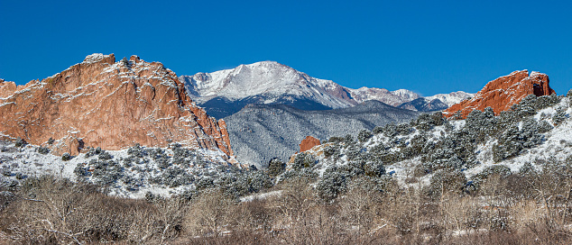 Fresh snow caps Pikes Peak viewed from the snow capped red rocks of Garden of the Gods.