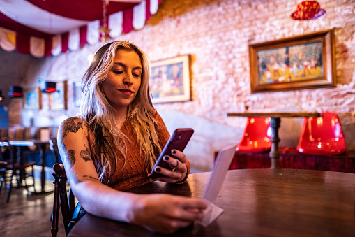 Young woman using the mobile phone to see digital menu at a restaurant
