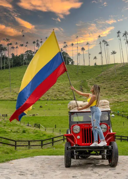 Woman with the flag of Colombia on top of the Willys Jeep