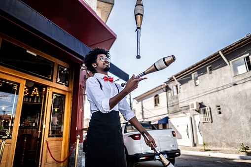 Waiter juggling with pins in front of reastaurant