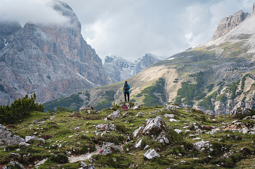 Rear-view of unrecognizable Caucasian man, admiring view of Dolomites Tre Cime di Lavaredo, during his hike