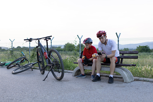 Father and son enjoying a healthy snack after riding bicycles.