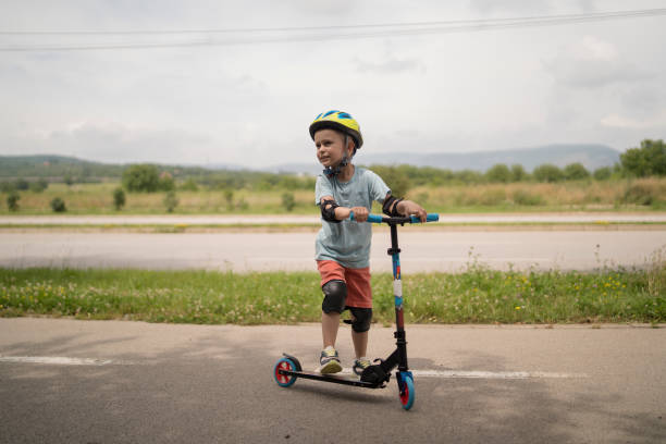 istock Little boy riding scooter. Kids ride kick board 1517235984