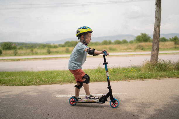 istock Little boy riding scooter. Kids ride kick board 1517236504