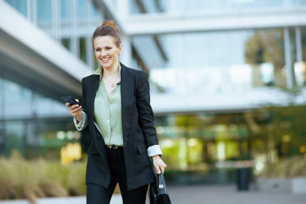 woman worker near business center using smartphone and walking stock photo