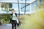 woman employee near business center using phone and walking
