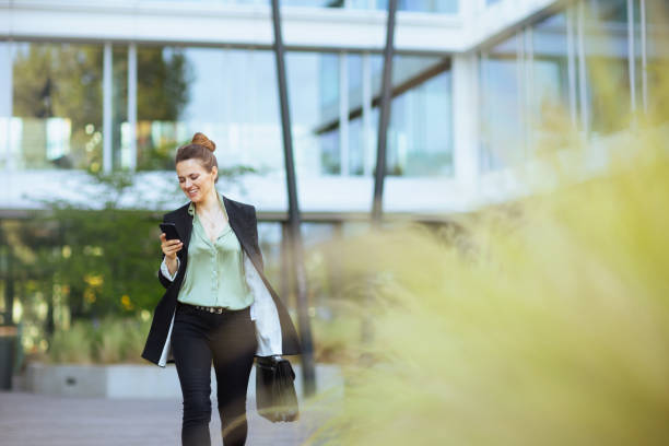 woman employee near business center using phone and walking stock photo