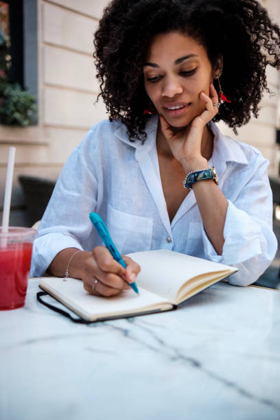 istock Smiling woman writing on diary outdoors. 1517263299
