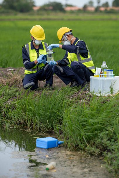 環境研究者は、有毒な流出、河川廃水のサンプリング、アジアの研究者が研究開発のために農地の水サンプルを収集するための運河水の状態を調査します。 - agriculture research science biology ストックフォトと画像