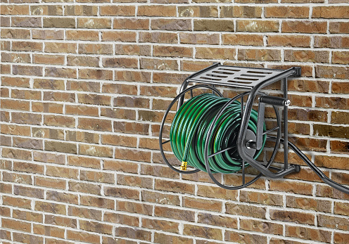 Metal wall mounted hose reel on a brick wall