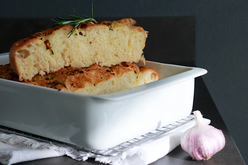 close up of italian garlic rosemary focaccia bread in white baking pan