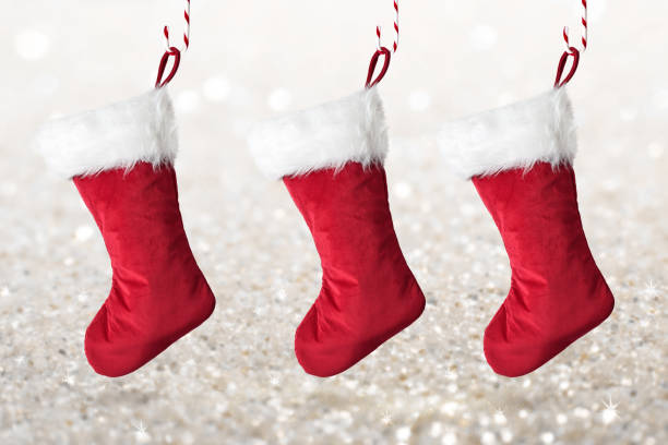 istock Three red Christmas stockings hanging on sparkly glittery background 1517383296