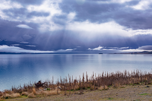 Photograph of early morning sun shining through rain clouds on Lake Tekapo on the South Island of New Zealand