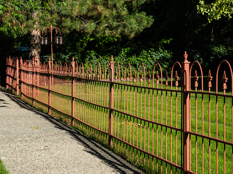 Ornate reddish orange wrought iron fence.
