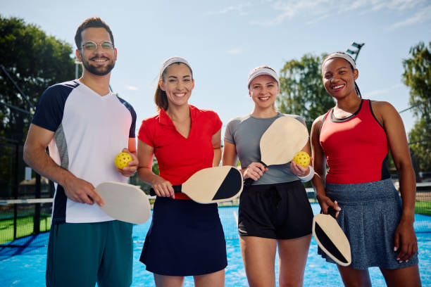 wielorasowa grupa szczęśliwych przyjaciół grających w pickleball i patrzących w kamerę. - mixed doubles zdjęcia i obrazy z banku zdjęć