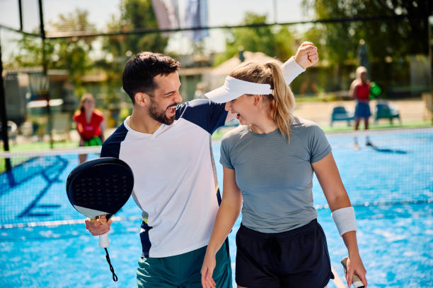 веселая спортивная пара празднует во время матча по падел-теннису на открытом корте. - two pairs стоковые фото и изображения