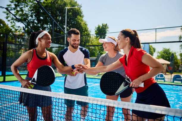 istock Happy paddle tennis players joining hands in unity while celebrating after the match. 1517472094