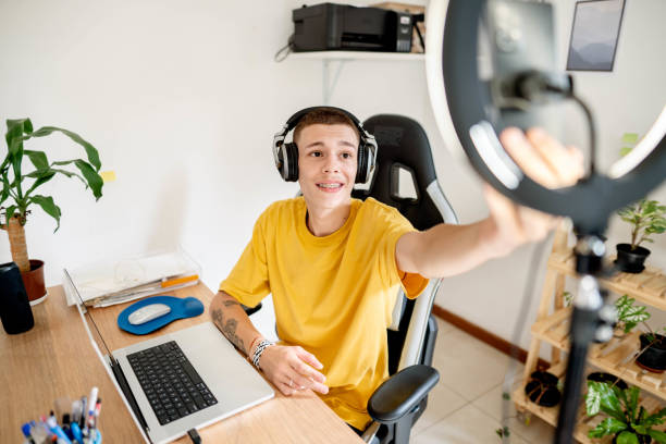 istock Smiling young man setting up for a live stream using a smart phone and laptop 1517506197