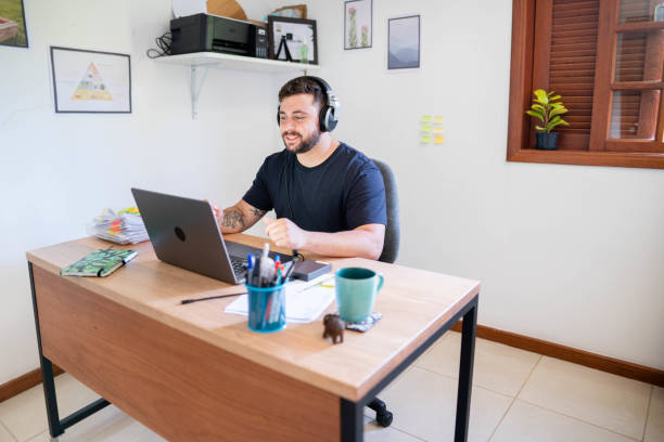 istock Man with headphones on a video call while working from home at his desk 1517507802