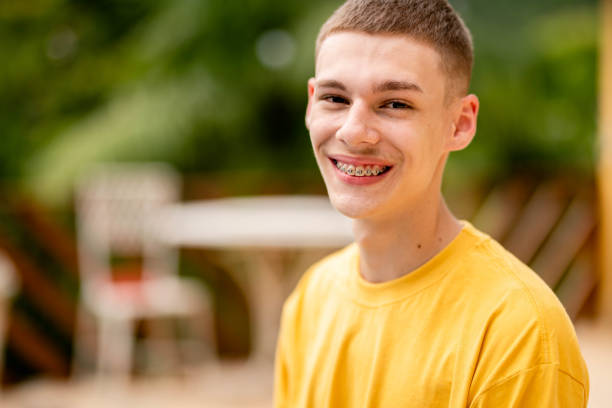 Portrait of a young man with braces smiling while relaxing outside on a patio at home in summer