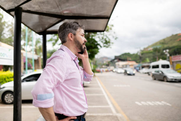 istock Man talking on cell phone while waiting at a bus stop in the city 1517589959