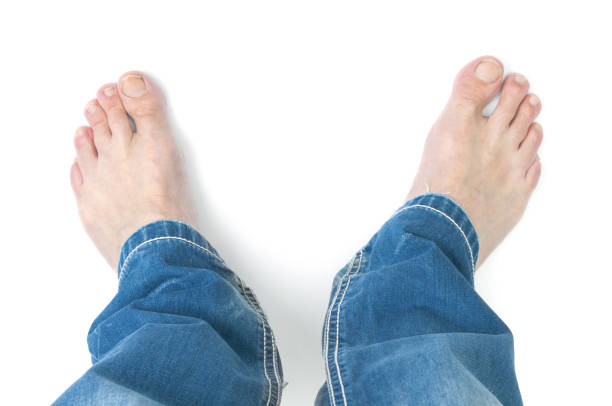 Barefoot man in blue jeans trousers on white background