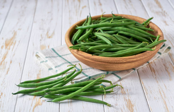 istock fresh green beans in a wooden bowl on a kitchen table, copy space for text. 1517671854