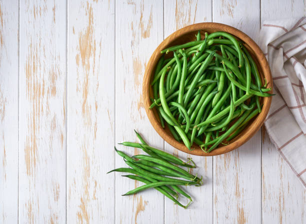 istock organic green beans in a bowl on a white cuisine table, top view. 1517671871