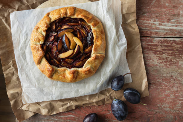 istock Plum open pie over baking paper top view on wooden table 1517717086