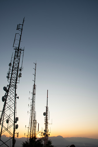 radio and television telecommunication antenna towers with satellite dishes at sunset or sunrise in mountain
