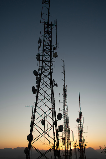 radio and television telecommunication antenna towers with satellite dishes in late afternoon sunset or sunrise